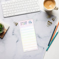 A product mockup of a notepad formatted with wide lines and faint checkboxes against a marble desk pad. The title says "Oh Sh*t, I made a List". It features a panicking bluebird to the right of the title.
