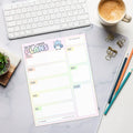 A product mockup of a weekly planner notepad with pastel rainbow colors. The title says "Oh Sh*t, I made plans". There is a panicking bluebird featured to the right of the title.