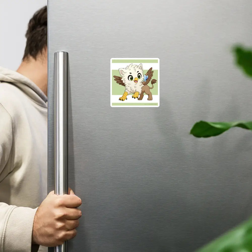 A product mockup of the 4x4" magnet featuring Echo the Griffin hanging on a stainless steel refrigerator door