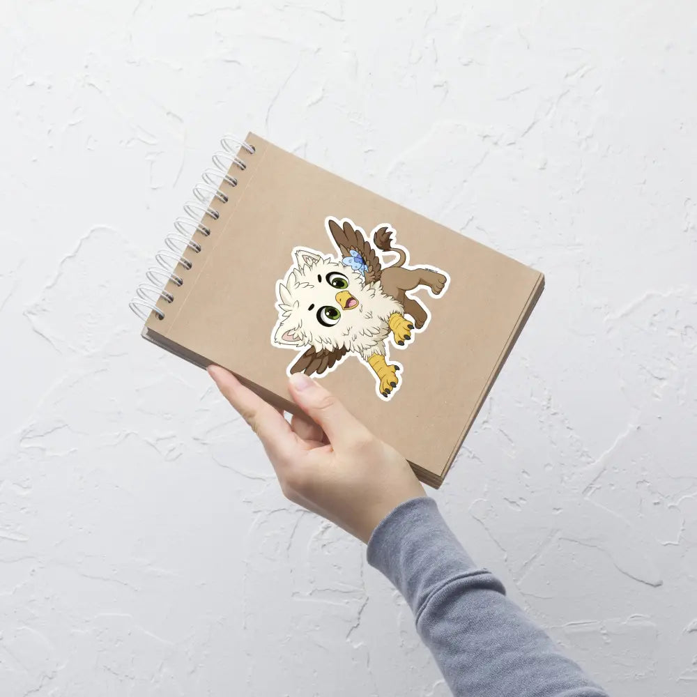 A product mockup of a 5x5" vinyl sticker on a brown notebook cover, featuring Echo the Griffin.