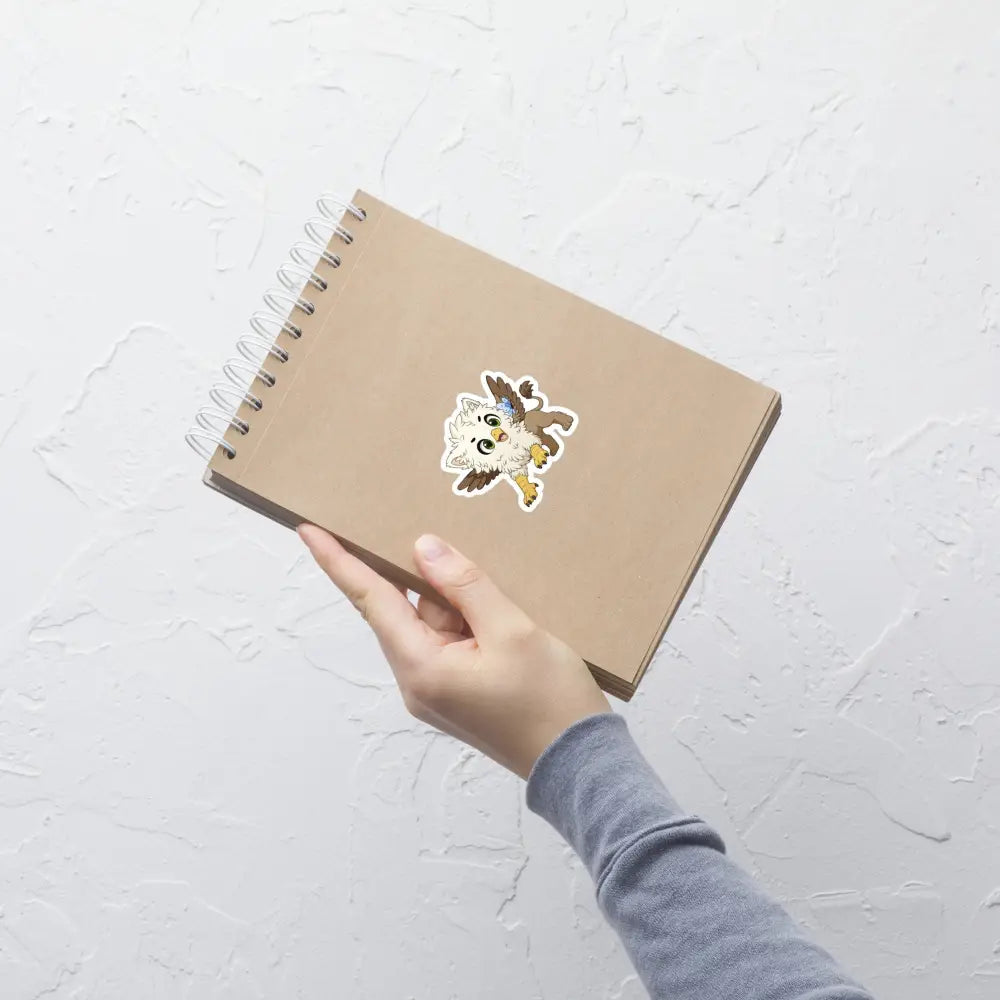 A product mockup of a 3x3" vinyl sticker on a brown notebook cover, featuring Echo the Griffin.