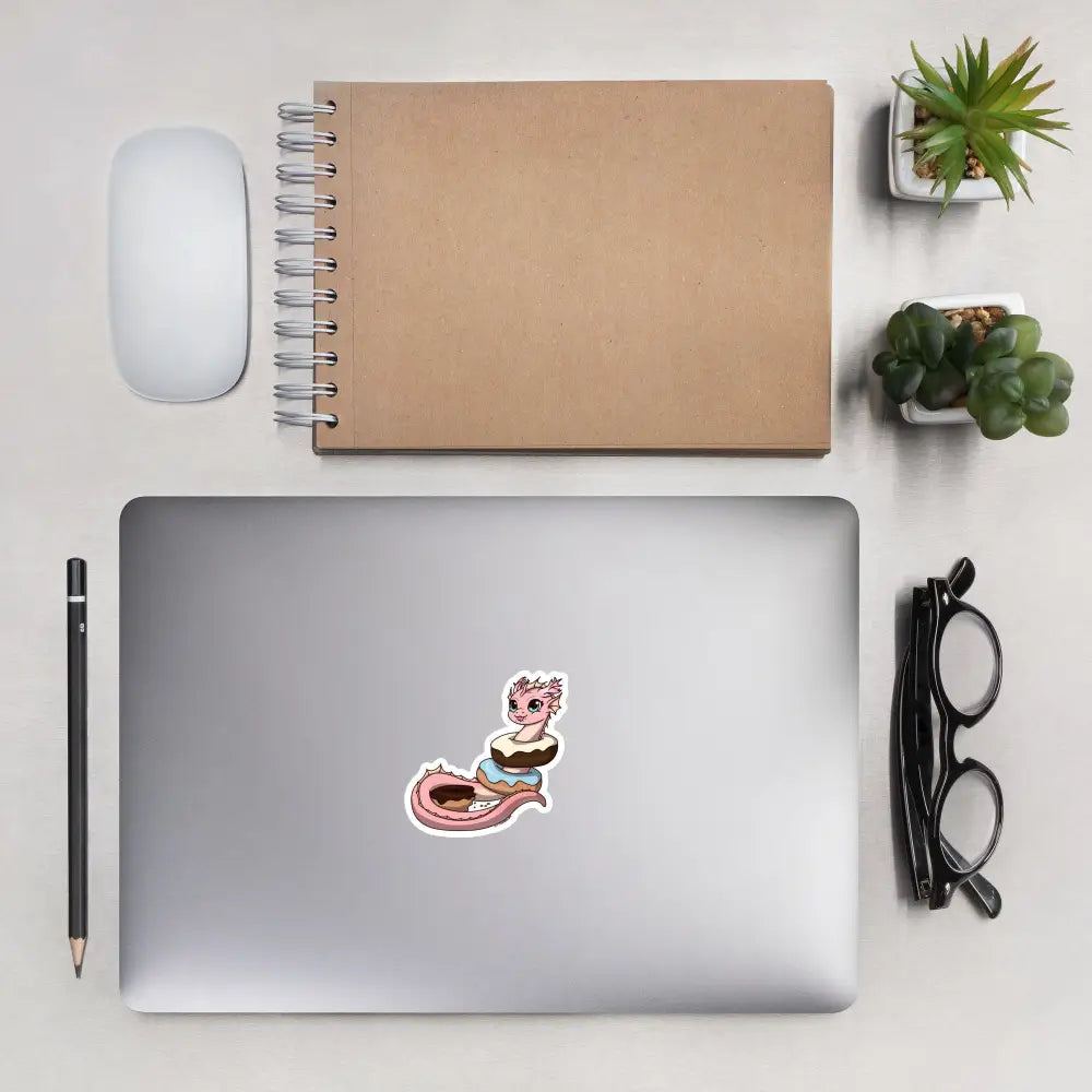 A product mockup of a 3x3" vinyl sticker on a silver laptop lid, featuring Pearl the Coral Dragon.