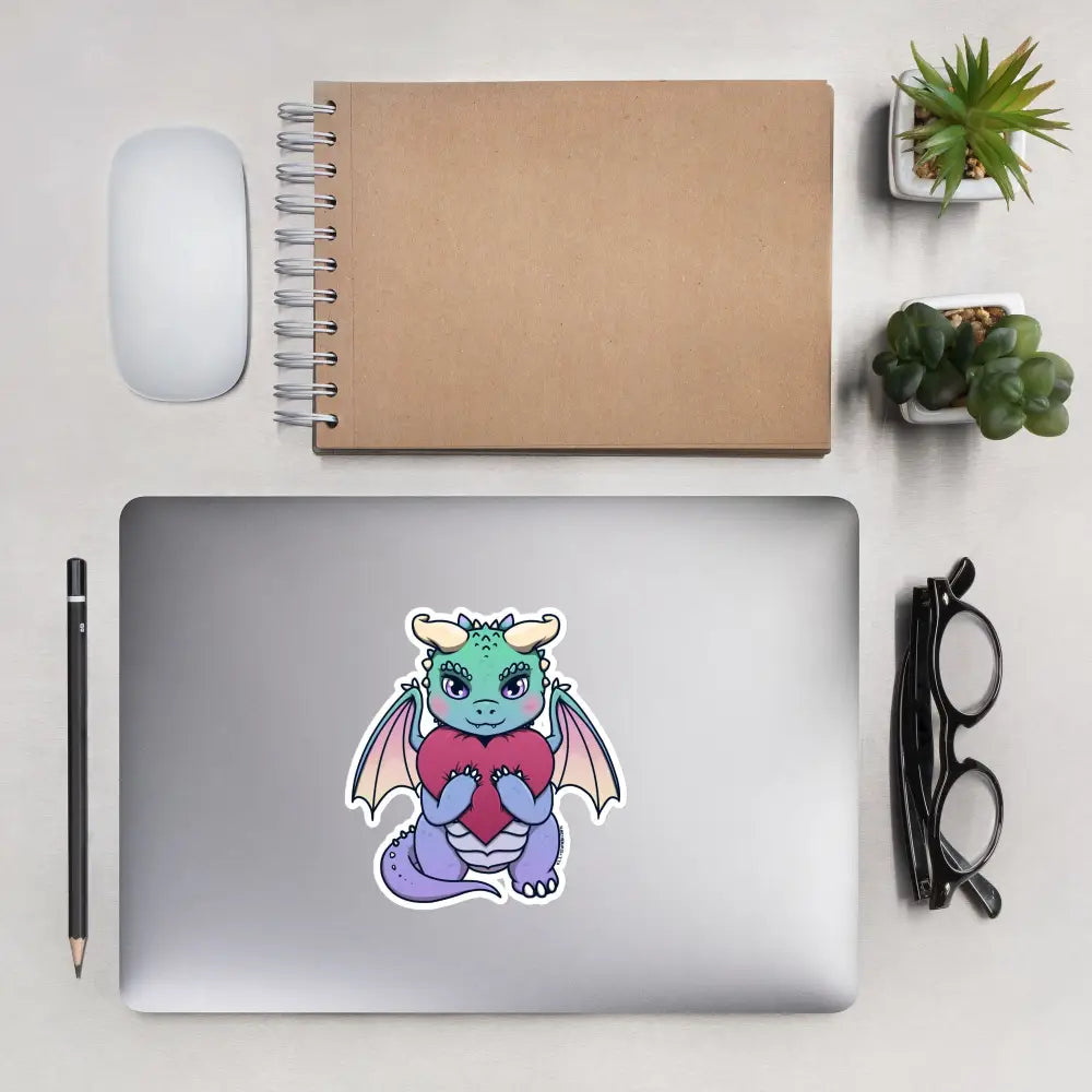 A product mockup of a 5x5" vinyl sticker on a silver laptop lid, featuring Vivian the Dragon.